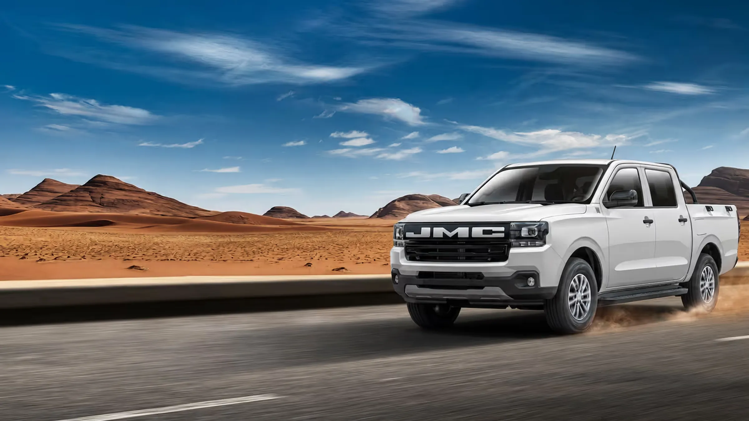 Pick-up JMC Vigus double cabine blanc roulant sur une route dans un paysage désertique