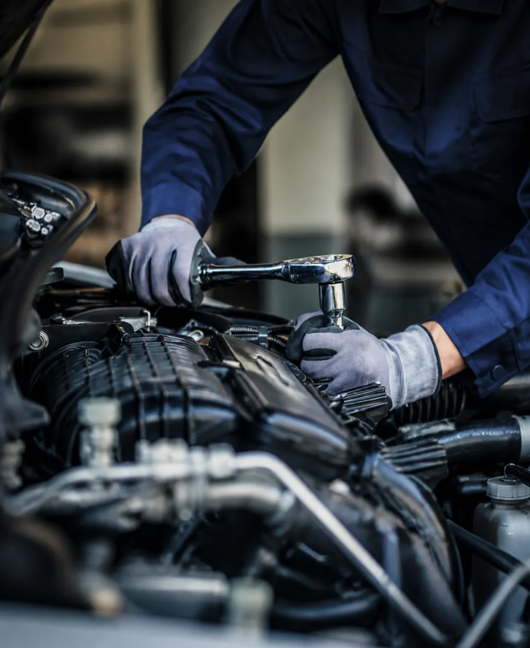 Technicien serrant une pièce dans le moteur d'un véhicule avec une clé à cliquet